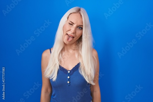 Caucasian woman standing over blue background sticking tongue out happy with funny expression. emotion concept. © Krakenimages.com