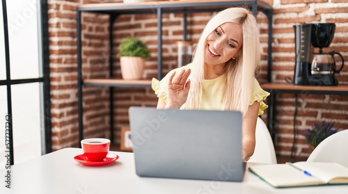 Caucasian woman doing video call with laptop looking positive and happy standing and smiling with a confident smile showing teeth