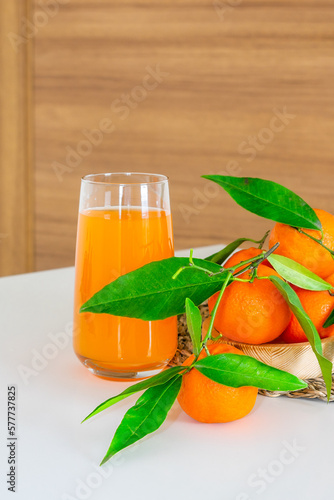 A glass of orange juice, fresh fruits of oranges and tangerines.