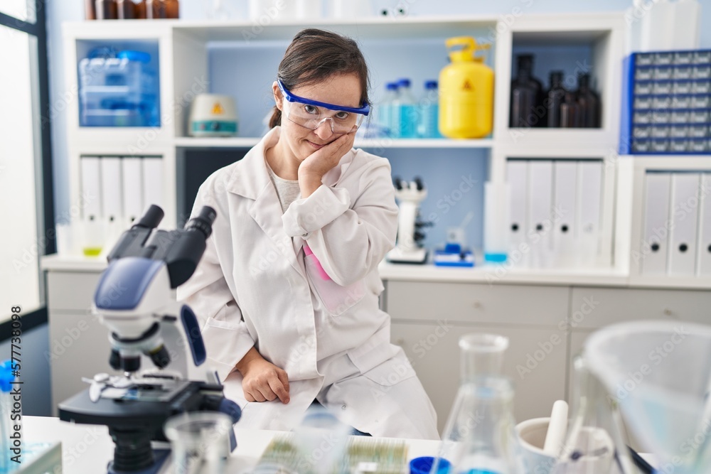 Hispanic girl with down syndrome working at scientist laboratory thinking looking tired and bored with depression problems with crossed arms. Hispanic girl with down syndrome working at scientist laboratory thinking looking tired and bored with depression problems with crossed arms.