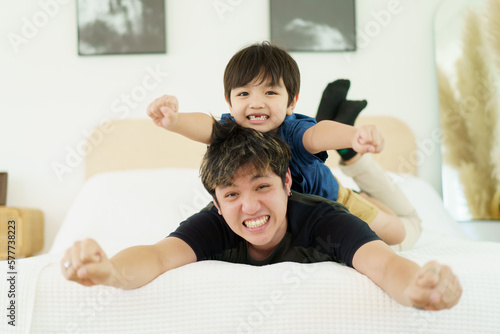 Happy Asian people family, a lovely little young boy playing with father in bedroom together. Father and son playing in bedroom.