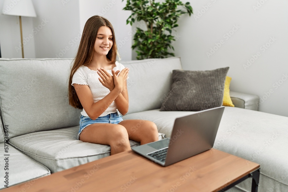 Adorable girl having video call communicating with deaf language sitting on sofa at home