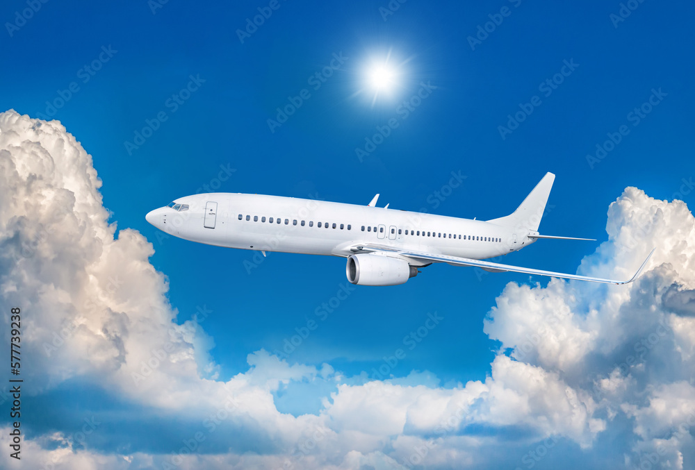 White passenger airliner fly in the air above scenic clouds
