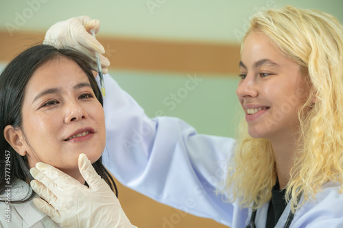 Woman Doctor Gently use hand syringe careful inject iller Botox liquid through skin patient for cosmetic beauty at cosmetic surgery department in hospital clinic.