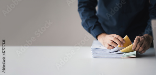 Фотография Businessman hand pick up stack overload documents, trying to organize and categorize the document in office room