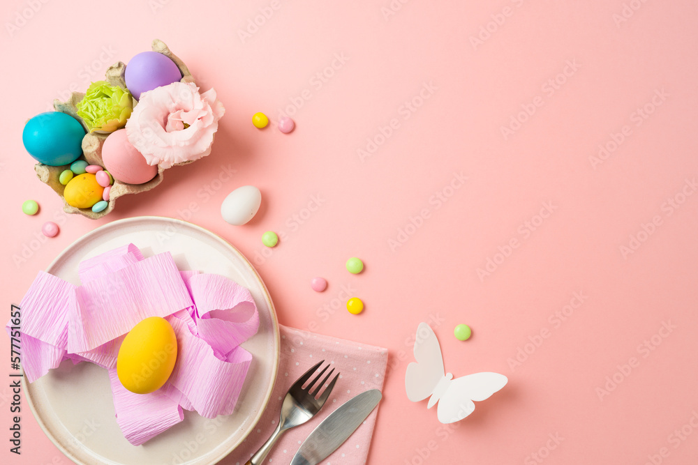 Easter holiday festive table setting with plate, easter eggs and party decorations on pink background. Top view, flat lay