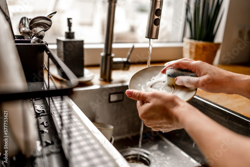 Quadro su tela Girl washing dishes at kitchen at home