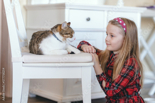 A blonde little girl and her kitty. Girl in red with her cat. 