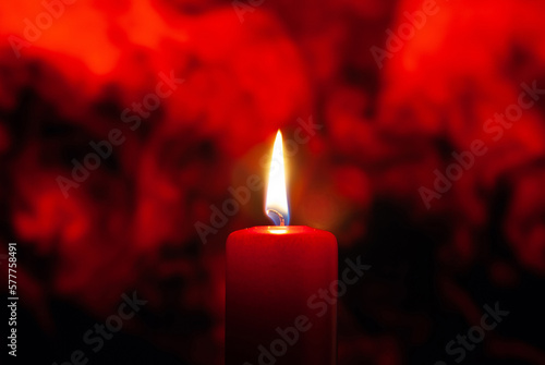 A candle burns against a background of red smoke. For ceremonies.