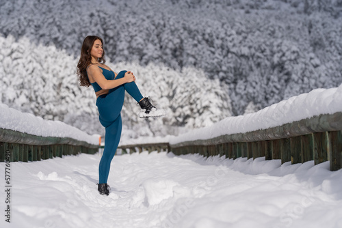 woman doing stretching exercise in snowy forest.