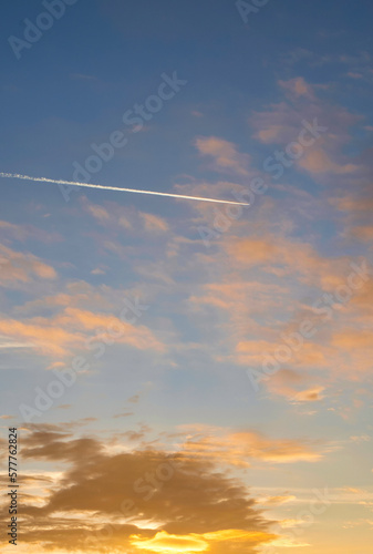 clouds in the sky at sunrise and the trail of a passing plane