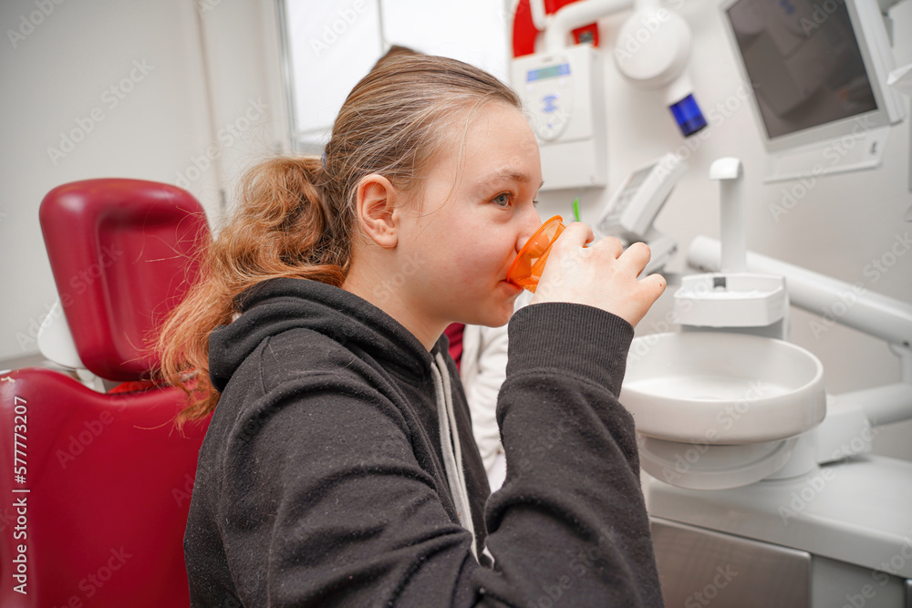 The girl rinses her mouth with water after examining and treating her teeth in the oral cavity at the dentist. The girl rinses her mouth with water after examining and treating her teeth in the oral cavity at the dentist.