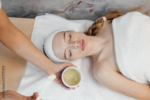 Close-up portrait of woman getting spa facial massage treatment with moisturising cream at beauty spa salon. Natural skin care cosmetic. Health care, beauty Cosmetologist applying mask on woman's face