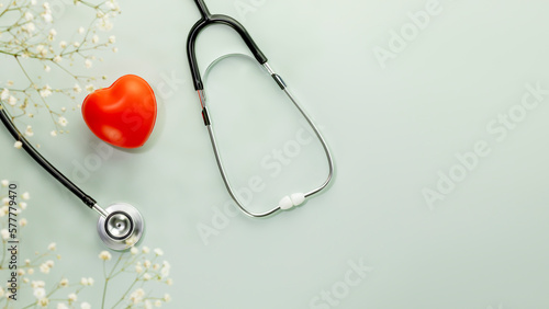 Red heart love shape hand exercise ball with stethoscope on blue background with flowers. Health care, organ donation, love and family insurance concept, world heart day. Flat lay, copy space photo