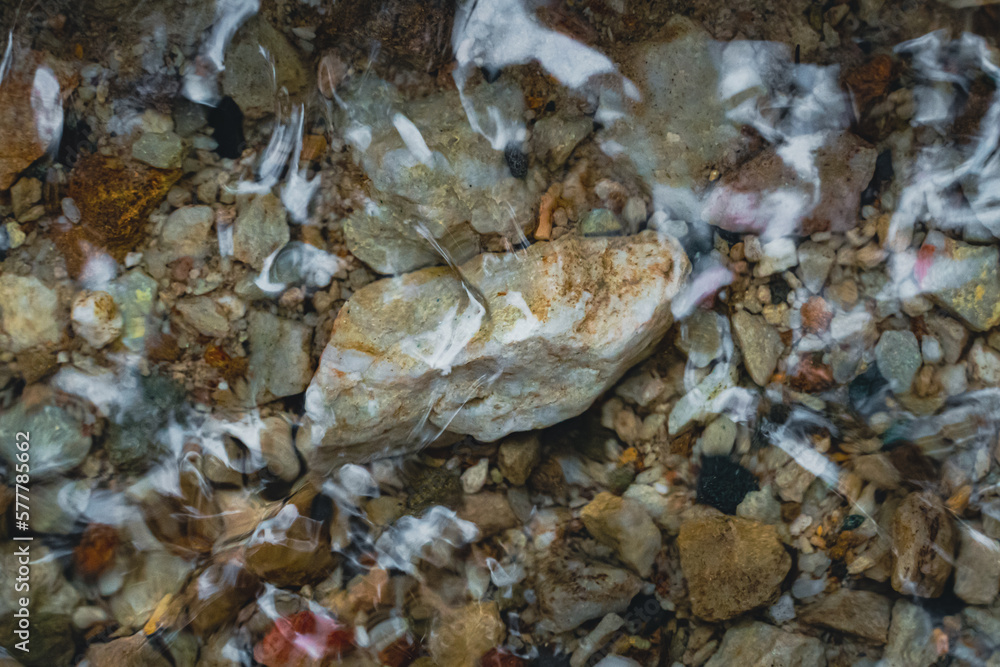 Obraz premium big and small stones under the clear water in the stream