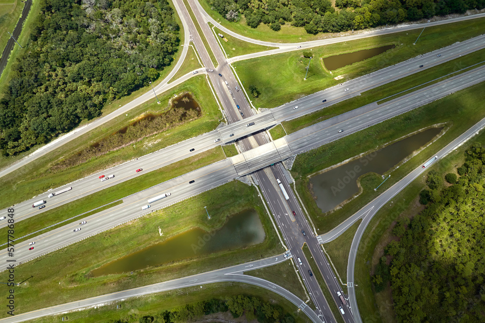 Aerial view of freeway overpass junction with fast moving traffic cars and trucks. Interstate transportation infrastructure in USA