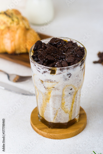 Iced coffee latte with crumble chocolate biscuit on wood coaster and white background