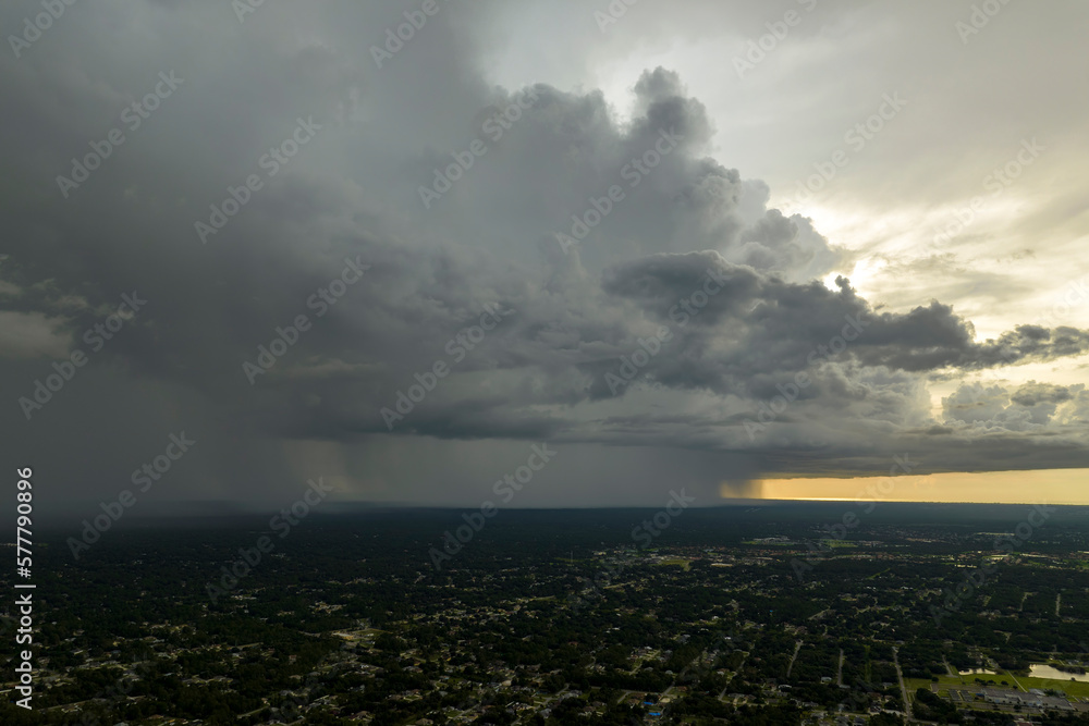 Dark stormy clouds forming on gloomy sky during heavy rainfall season over suburban town area