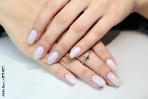 Gentle nude manicure on her nails. Classic bridal nail design.