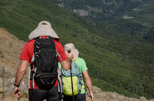 dos personas haciendo trekking en la montaña con gorros mochilas y bastones photo