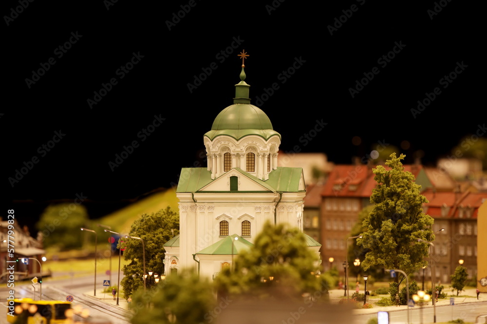 Orthodox church on the street of the evening city. Landscape layout with railroad, cars, residential and industrial buildings. Monuments of architecture and sights. Hobbies of building miniatures