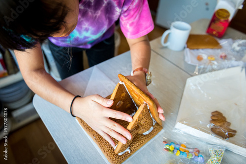 Young asian girl building ginger bread house in holiday season