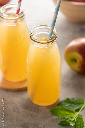 Apple juice glass bottles, with fresh red apples, wooden background.