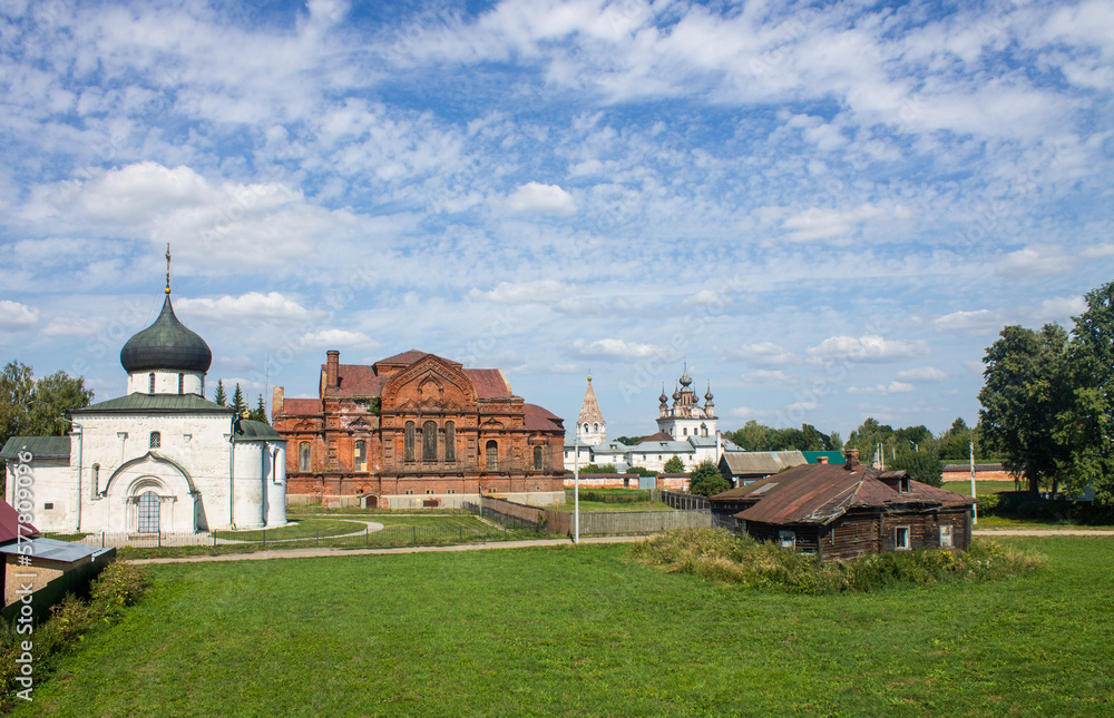 A beautiful urban landscape - the old town of Yuriev-polsky with ancient temples, a wooden hut and green trees on a sunny summer day and a space for copying