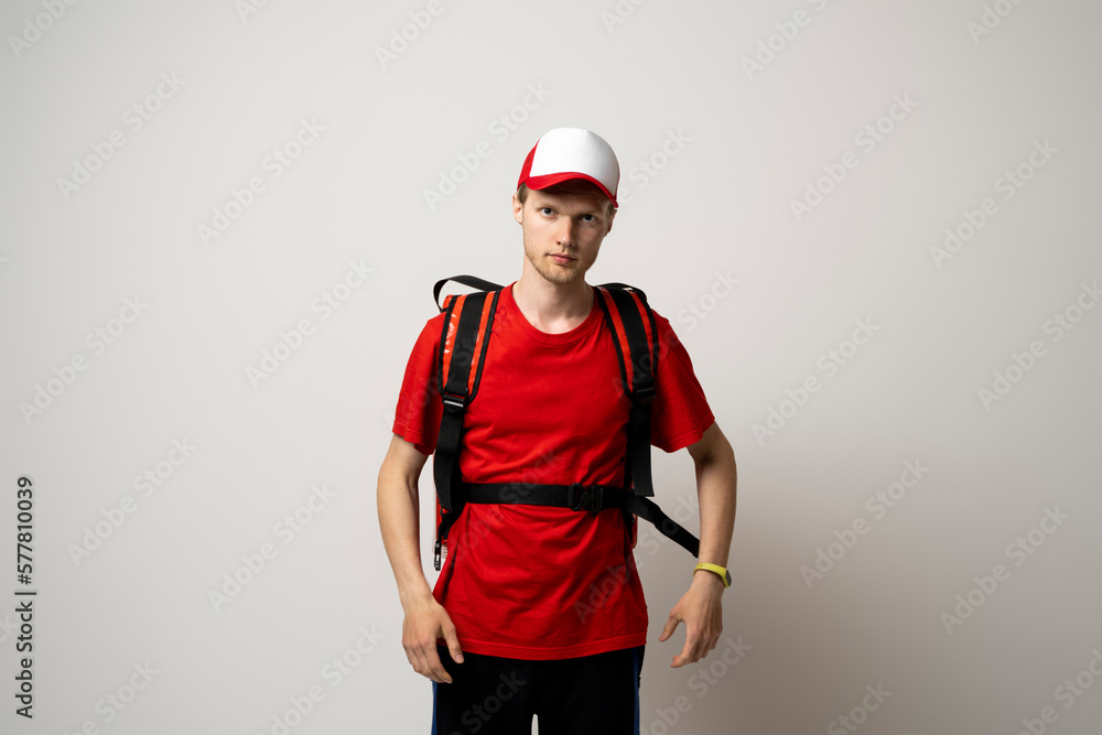 Delivery man in a red uniform carry thermal backpack full of food, groceries to the clients. Food delivery service. Delivery man in a red uniform carry thermal backpack full of food, groceries to the clients. Food delivery service.