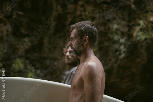 Man with a surfboard goes to the Uluwatu surf spot.