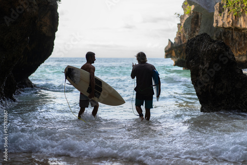 Man with a surfboard goes to the Uluwatu surf spot.