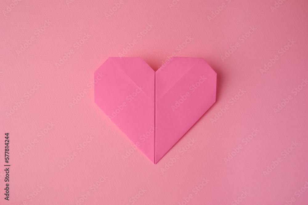 Origami art. Paper heart on pink background, top view