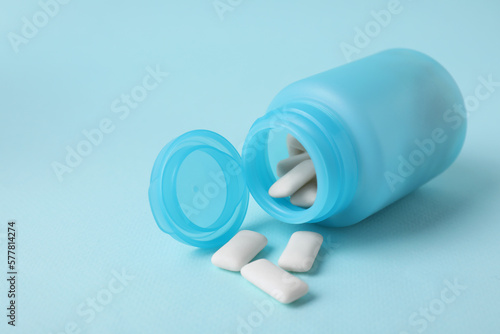 Color jar with chewing gums on light blue background, closeup. Space for text