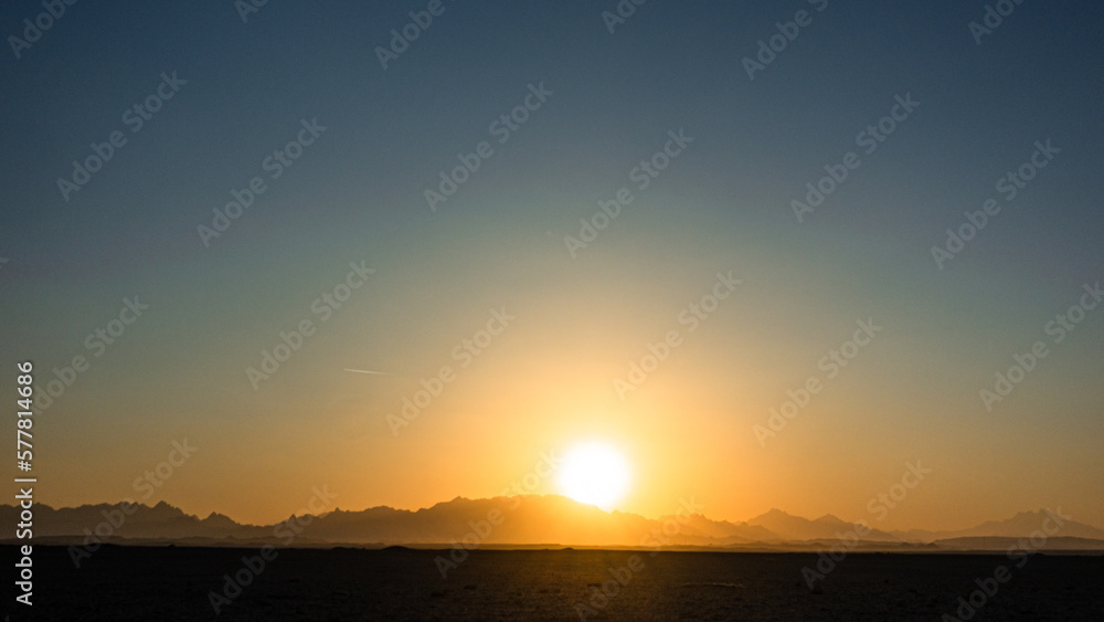 Beautiful clear big sun at sunrise or sunset against the backdrop of mountains. Africa.