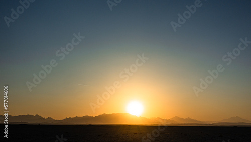 Beautiful clear big sun at sunrise or sunset against the backdrop of mountains. Africa.