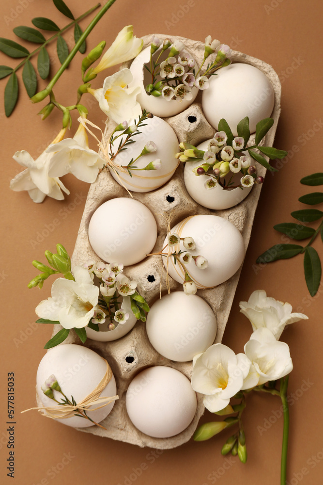 Festive composition with eggs and floral decor on brown background, flat lay. Happy Easter