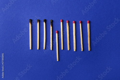 Burnt and whole matches on blue background  flat lay. Stop destruction concept