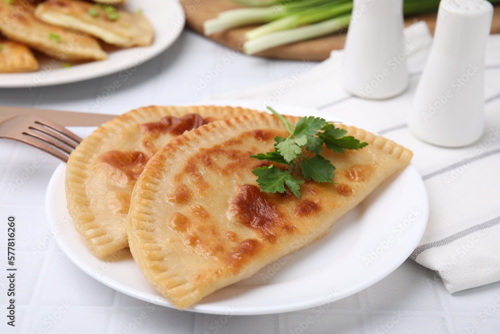 Delicious fried cheburek with cheese and parsley on white tiled table Delicious fried cheburek with cheese and parsley on white tiled table