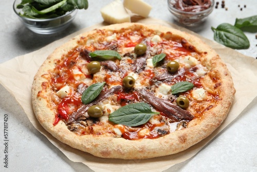 Tasty pizza with anchovies and ingredients on white table