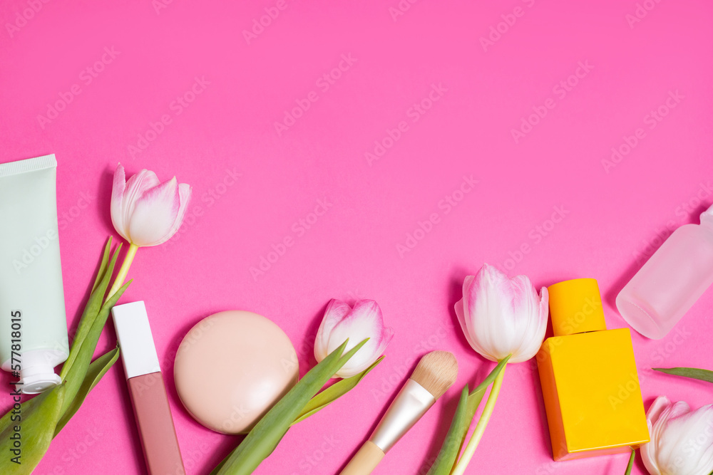 Beauty background with makeup cosmetic, perfume, flowers. Flat lay image on pink