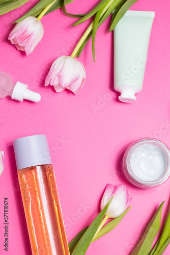 Beauty background with natural cosmetic, flowers. Flat lay image on pink