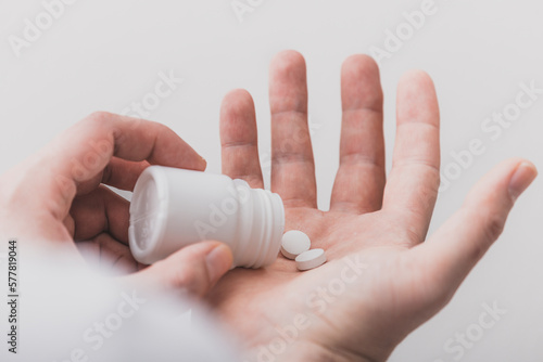 A close-up view of the hands with the pills. Dispensing pills from the bottle onto the palm of the hand