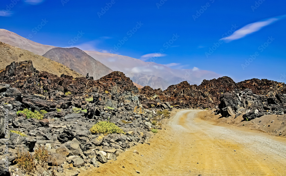 Empty coast sand dirt road track between rocks and mountains in wild dry arid desert landscape - Pan de Azucar, Chile