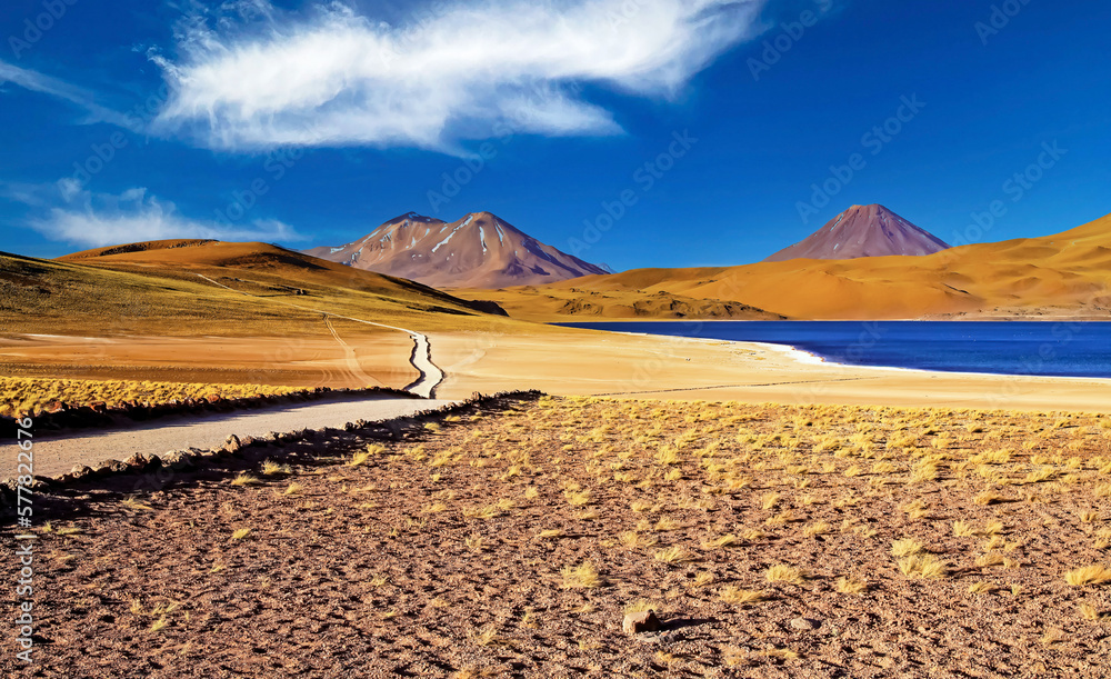 Beautiful spectacular dry colorful arid landscape, deep blue lake in andes high plains, hiking path, volcano Miniques - Laguna Miscanti, Atacama desert, Chile