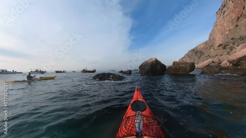 Sea kayaking day with a beautiful view of the wild landscape. Trip on Black sea. Group of paddlers in tunnels and rock, between cliffs, in caves. Kayaks on waves and calm water. Explore nature. photo