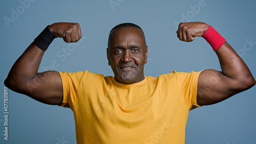 Portrait mature sports african man posing in studio gray background strong muscular athletic male athlete sportsman demonstrates biceps inflated triceps middle aged bodybuilder showing strong muscles