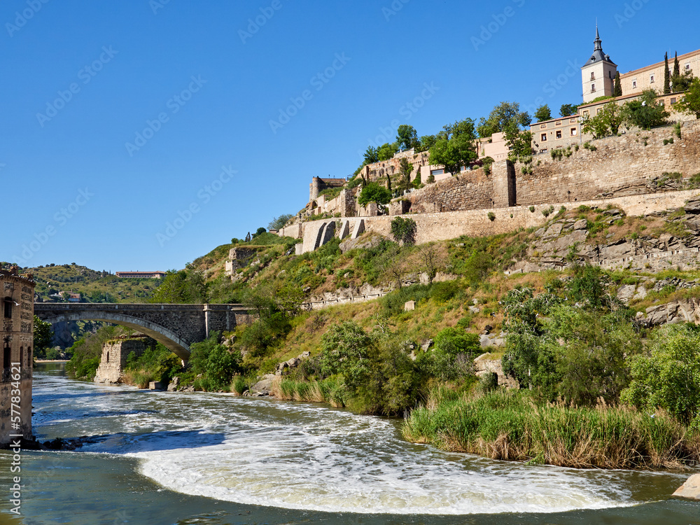 Landscape of Tagus river, an old stone bridge and the city of Toledo in a sunny spring day. Castilla La Mancha, Spain, Europe