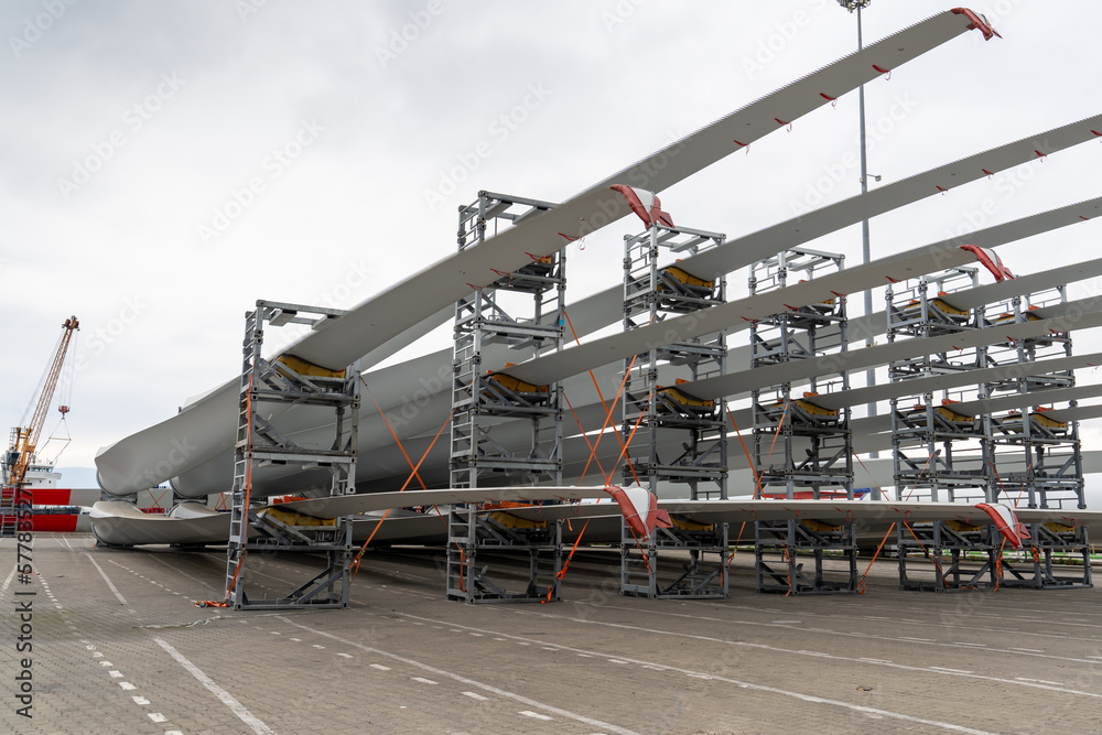 Naklejka premium Wind turbines with blades and bodies ready for installation, waiting in port to be transported to wind turbine farms for electricity generation