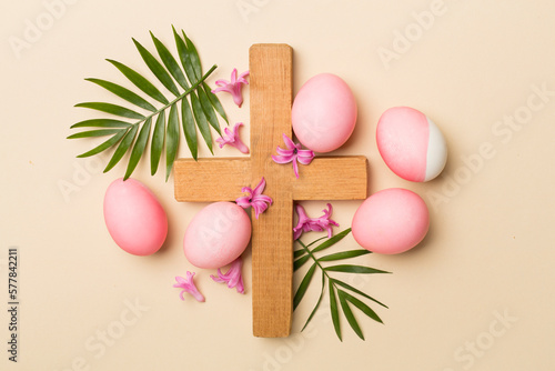 Valokuvatapetti Pink Easter eggs with cross and palm leaves on color background, top view