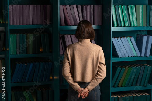 Higher education, training in complex specialties, concept. Natural sciences. A large amount of information. Student in the library against the background of bookshelves, laconic minimalistic style